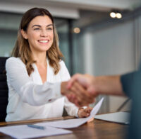 Happy mid aged business woman manager handshaking at office meeting. Smiling female hr hiring recruit at job interview, bank or insurance agent, lawyer making contract deal with client at work.
